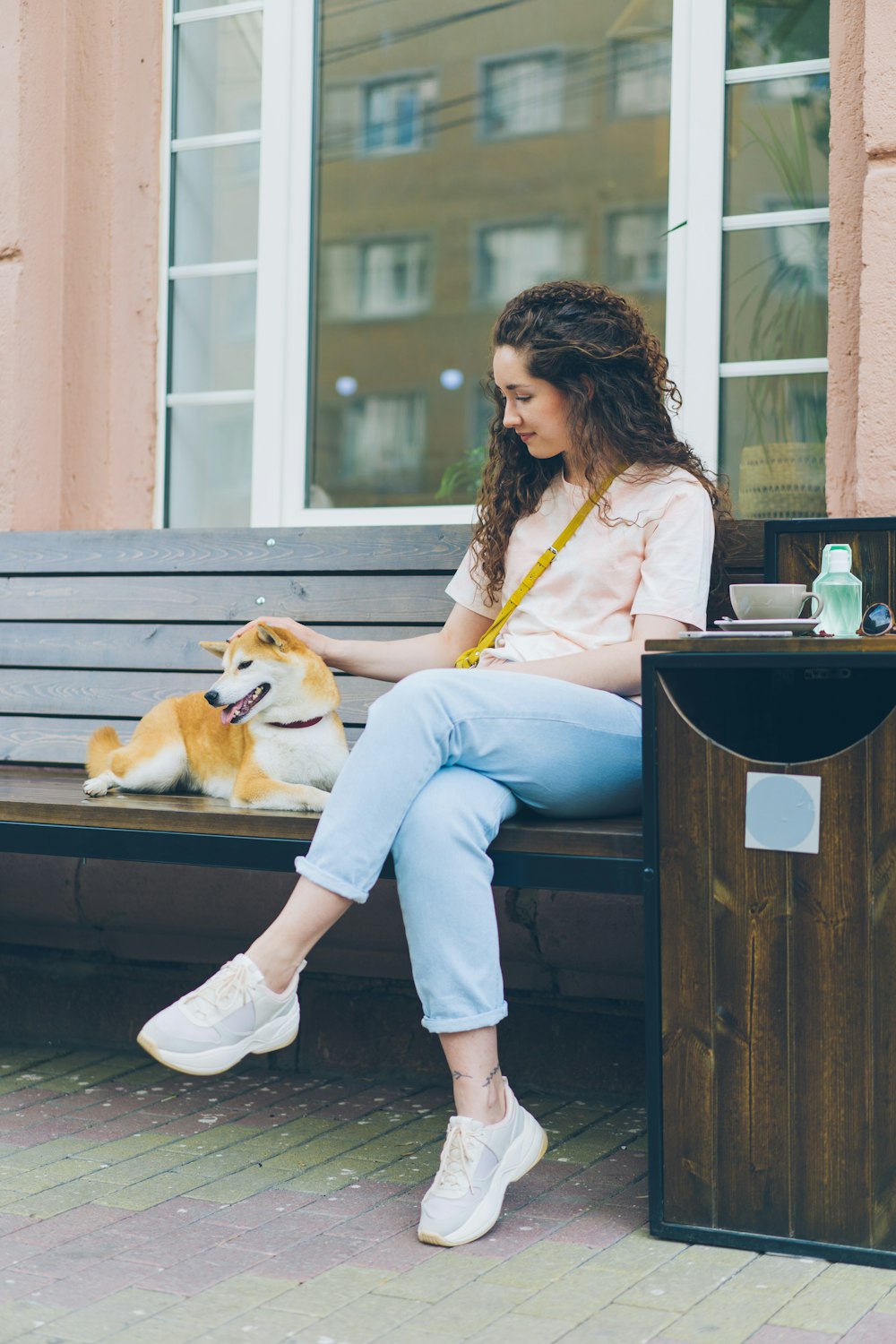 a woman sitting on a bench next to a dog