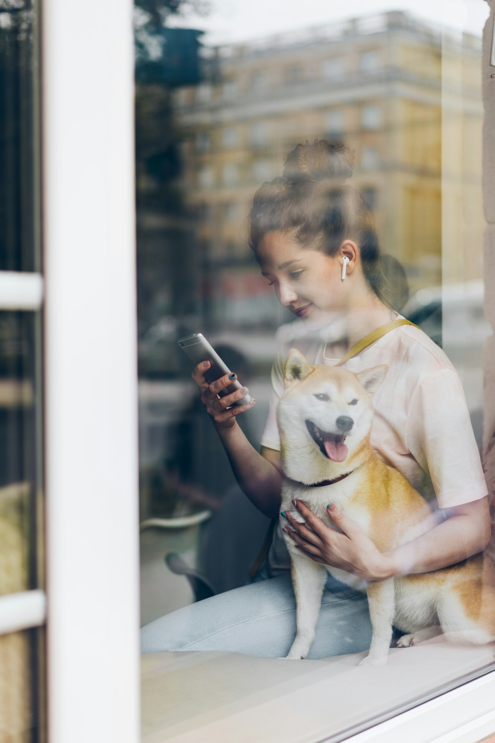 una donna seduta sul davanzale di una finestra con in braccio un cane