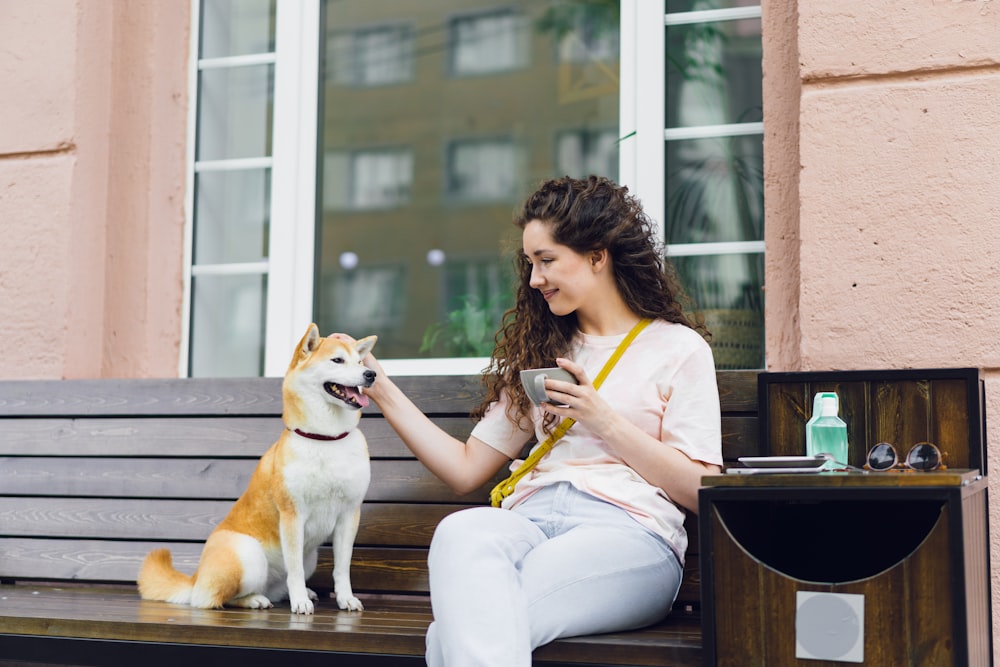 a woman sitting on a bench petting a dog