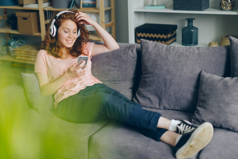 uma mulher sentada em um sofá ouvindo música