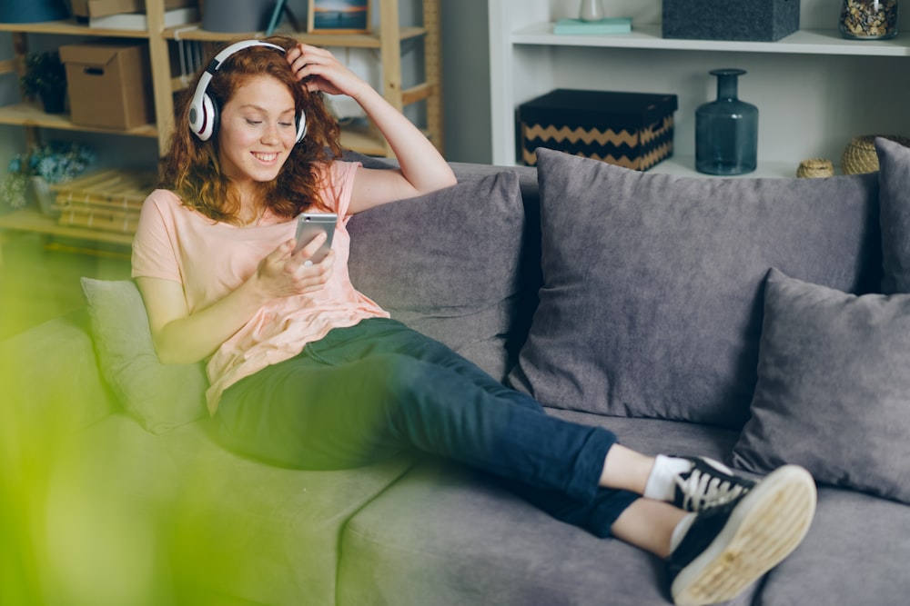 eine Frau sitzt auf einer Couch und hört Musik