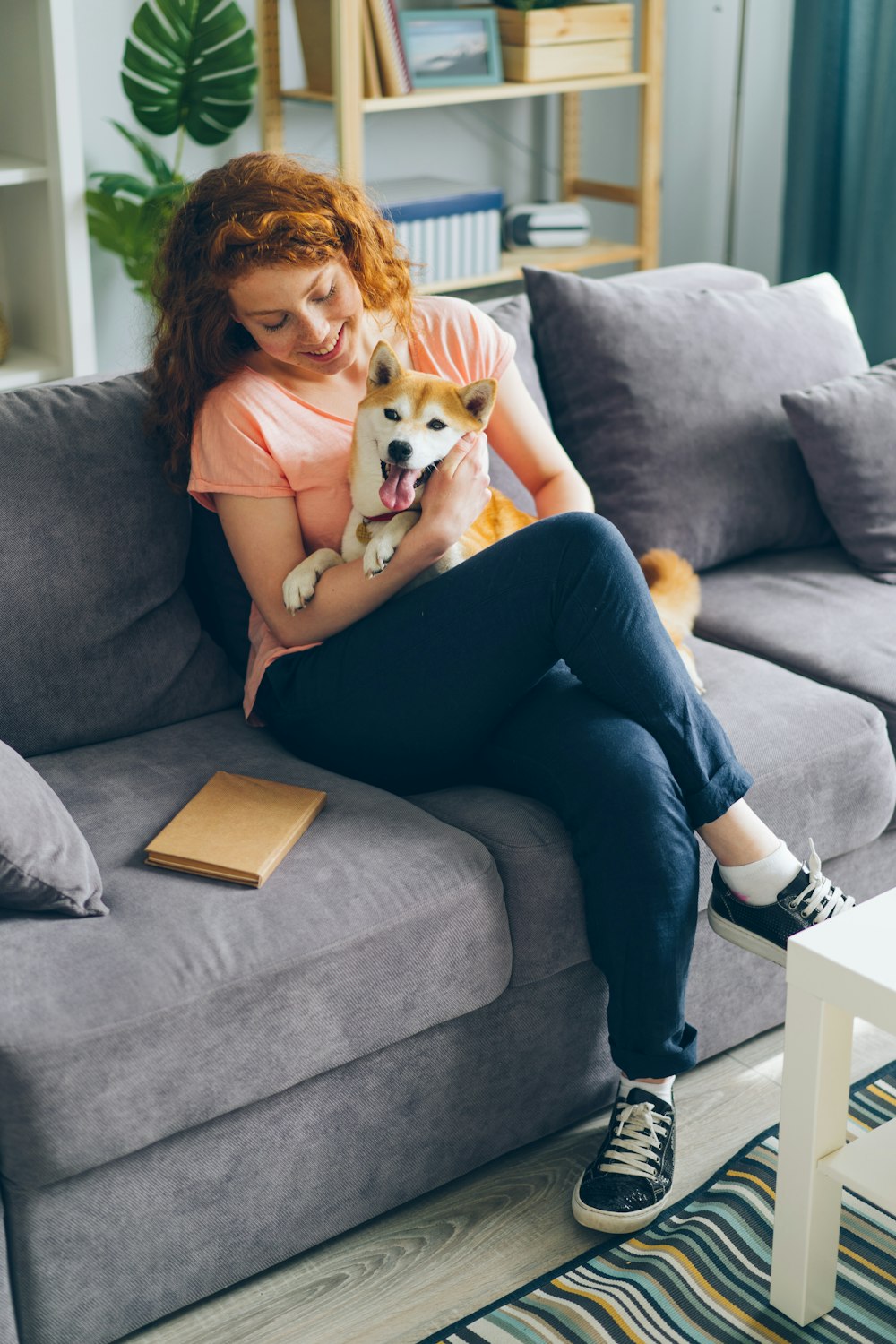 uma mulher sentada em um sofá segurando um cachorro
