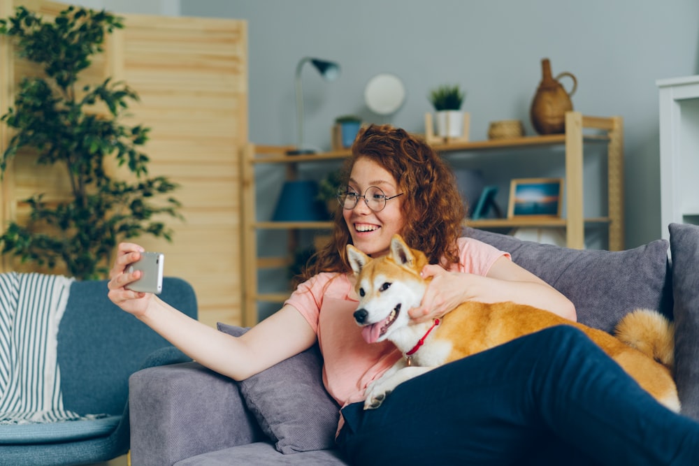 eine Frau, die auf einer Couch sitzt und einen Hund hält