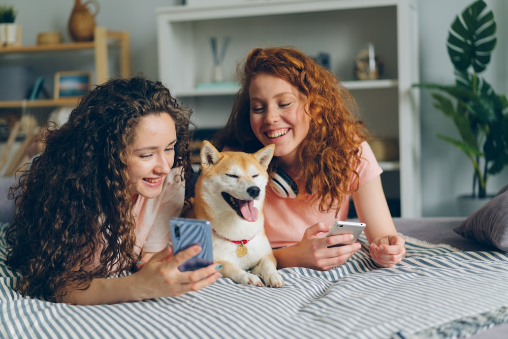 Dos mujeres acostadas en una cama con un perro