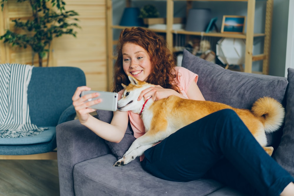 a woman sitting on a couch holding a dog