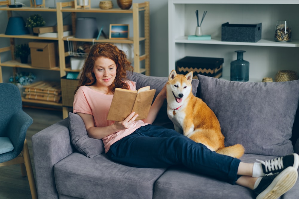 a woman sitting on a couch next to a dog