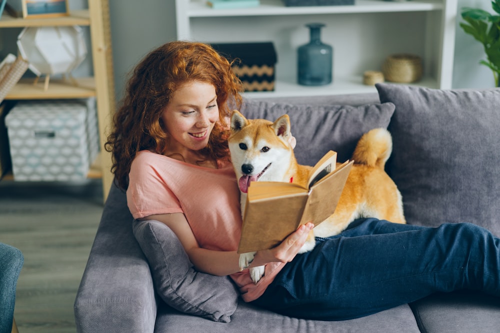 eine Frau, die auf einer Couch sitzt und einen Hund hält