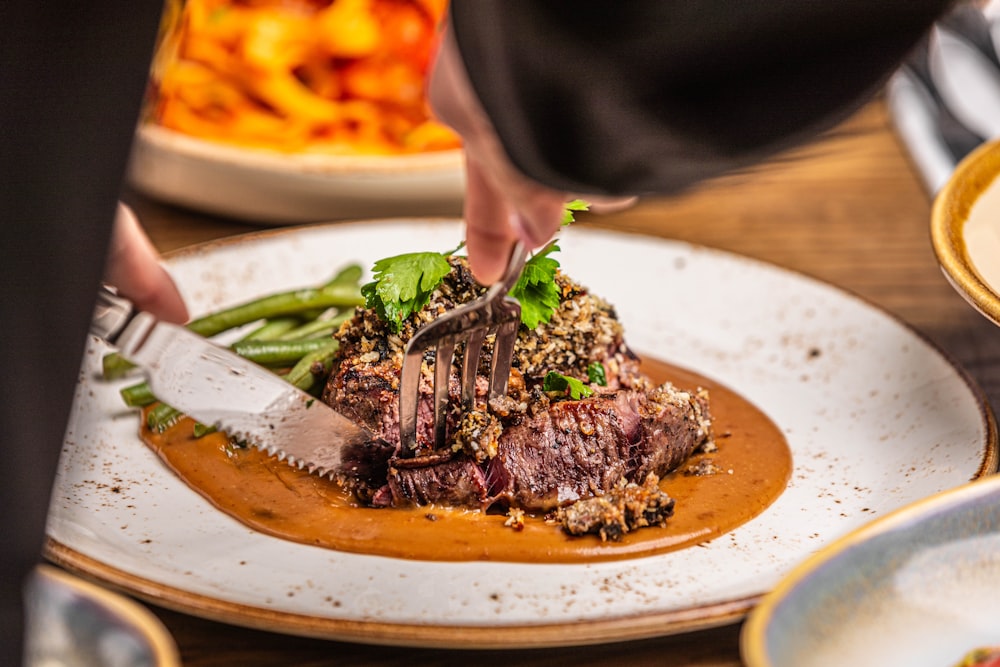 a person cutting a piece of meat on a plate