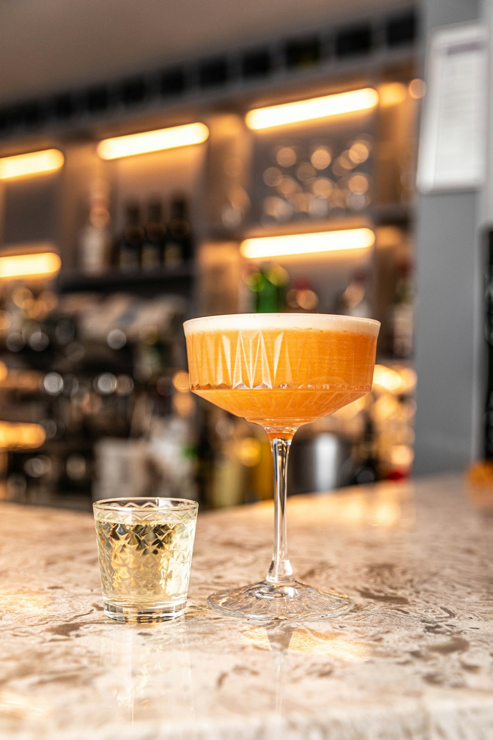 a drink sitting on top of a counter next to a shot glass