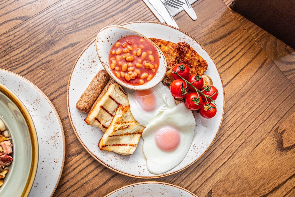 a plate of food with eggs, toast, tomatoes and beans