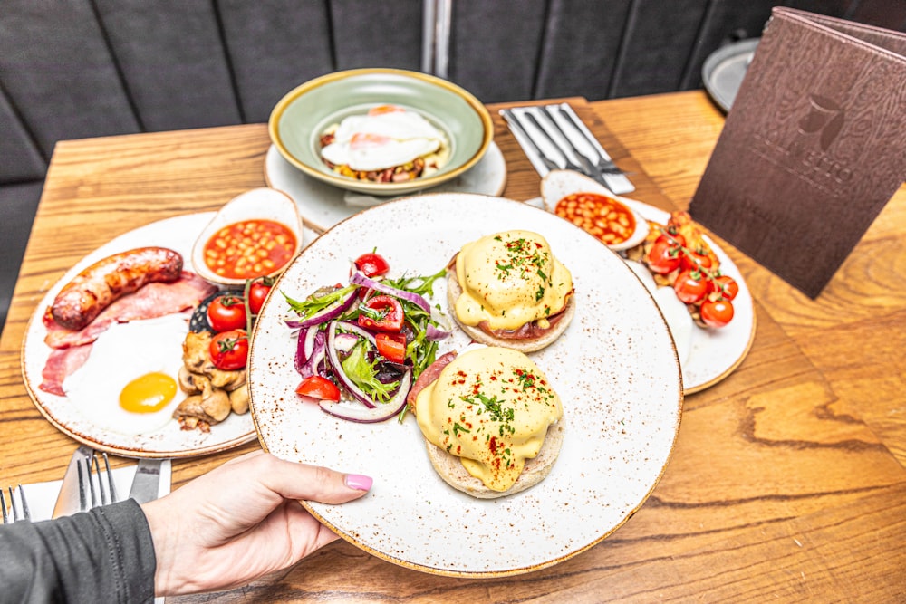 a person holding a plate of food on a table