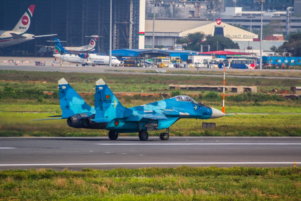 a blue fighter jet sitting on top of an airport runway