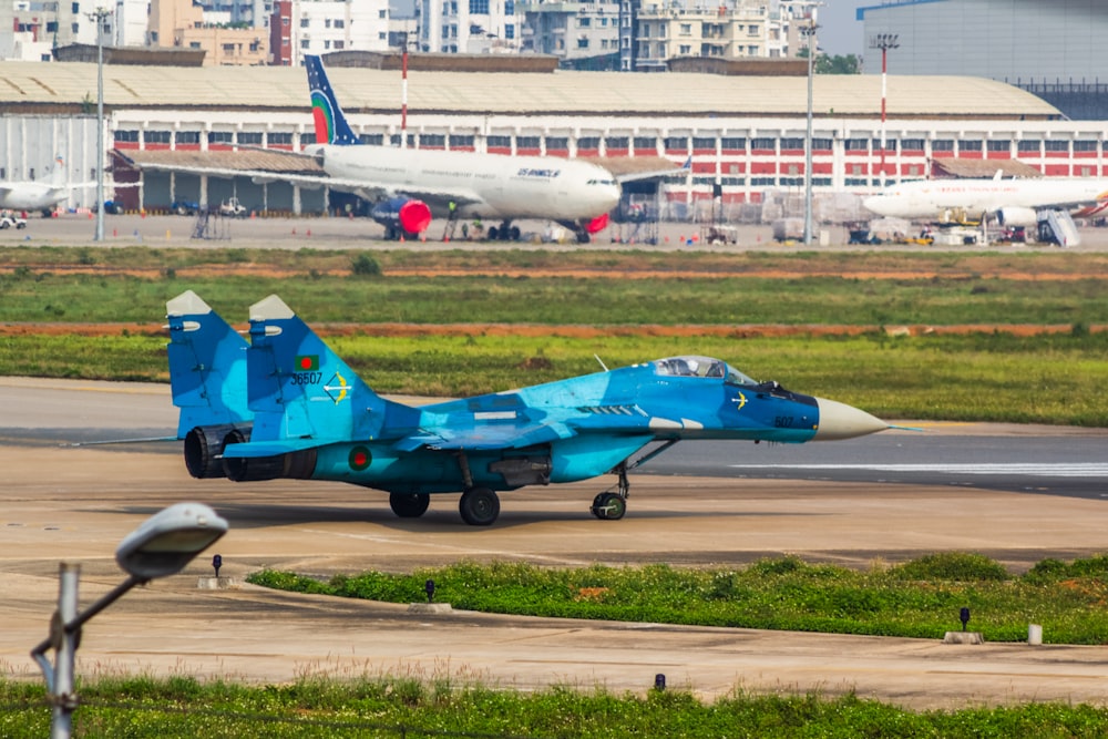 a blue fighter jet sitting on top of an airport runway