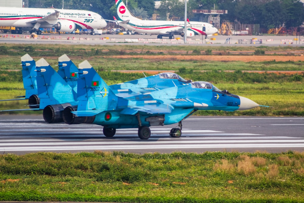 a blue fighter jet sitting on top of an airport runway