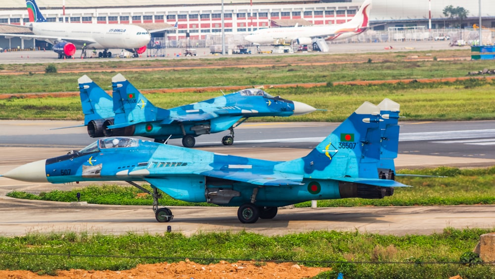 a couple of fighter jets sitting on top of an airport runway