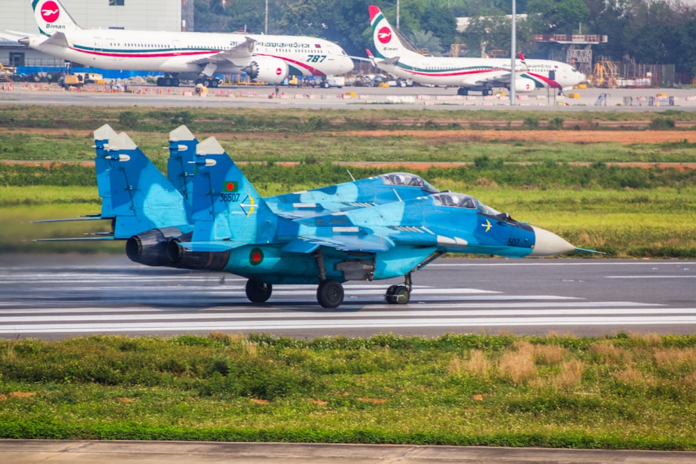 a blue fighter jet sitting on top of an airport runway