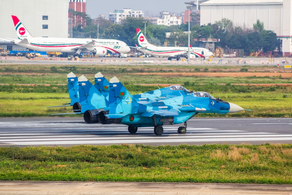 a blue fighter jet sitting on top of an airport runway