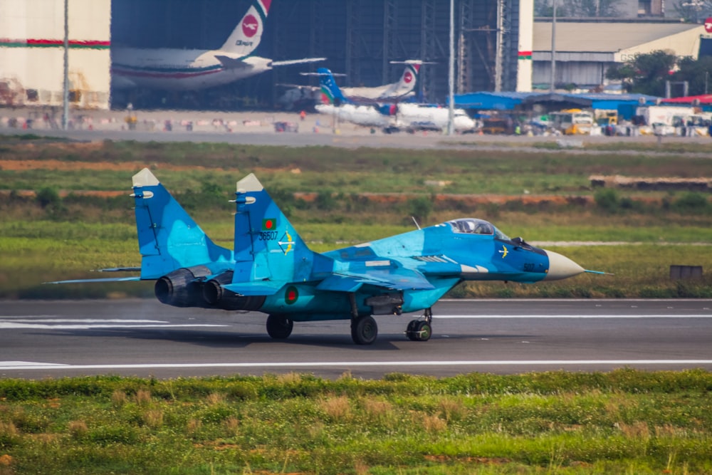 a blue fighter jet sitting on top of an airport runway