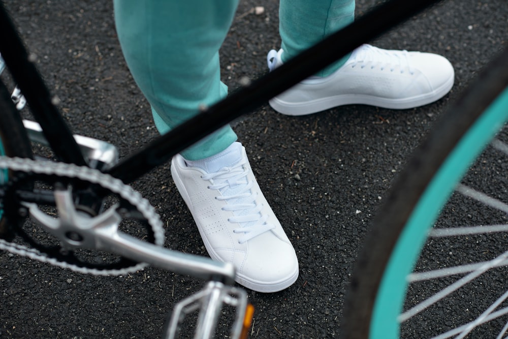 a person standing next to a bike wearing white shoes