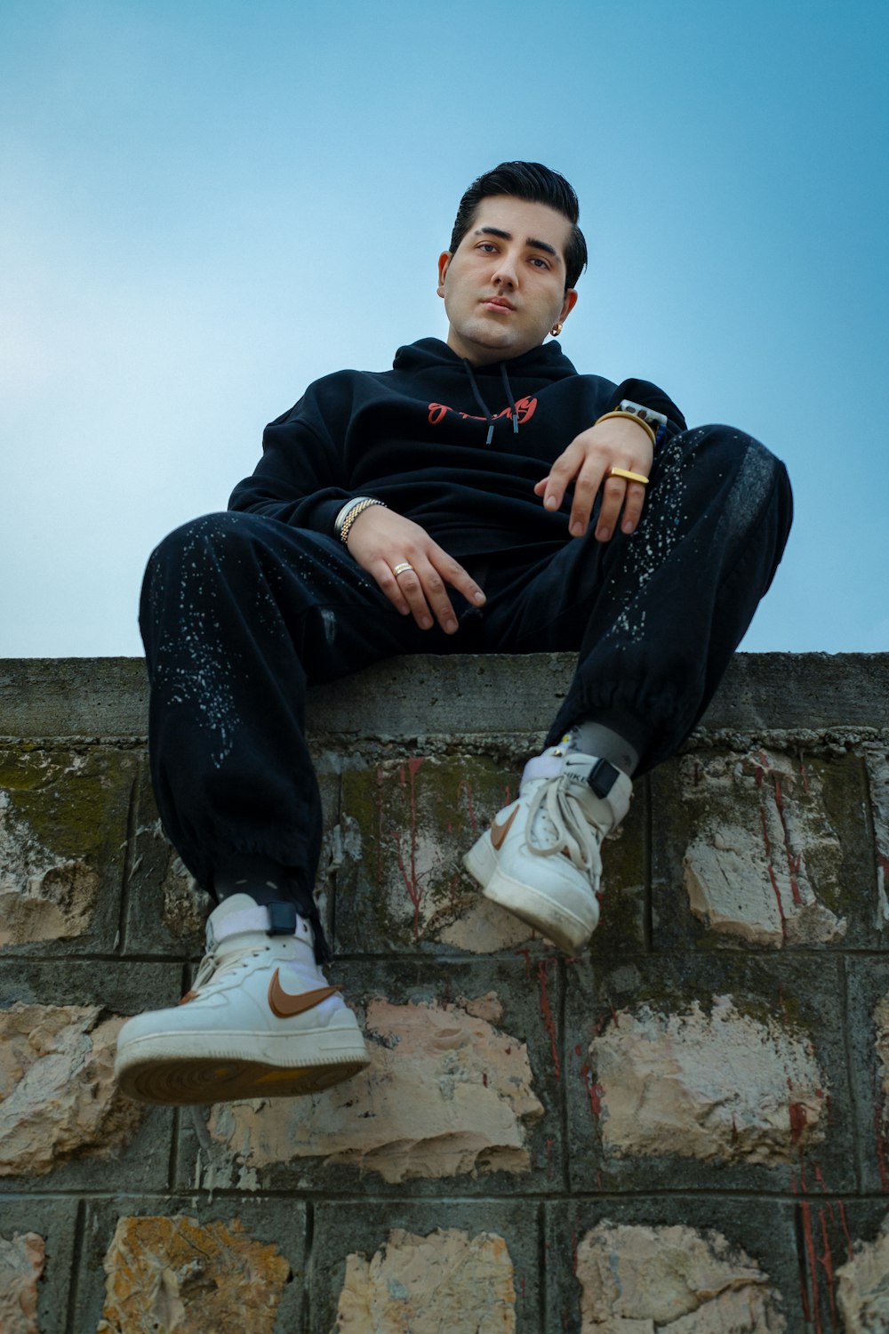 a man sitting on top of a brick wall