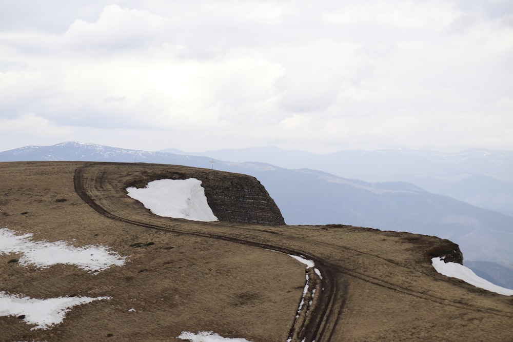 a dirt road on top of a mountain with snow on the ground