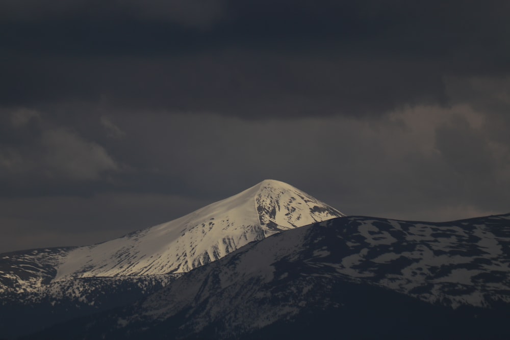 a mountain covered in snow under a cloudy sky