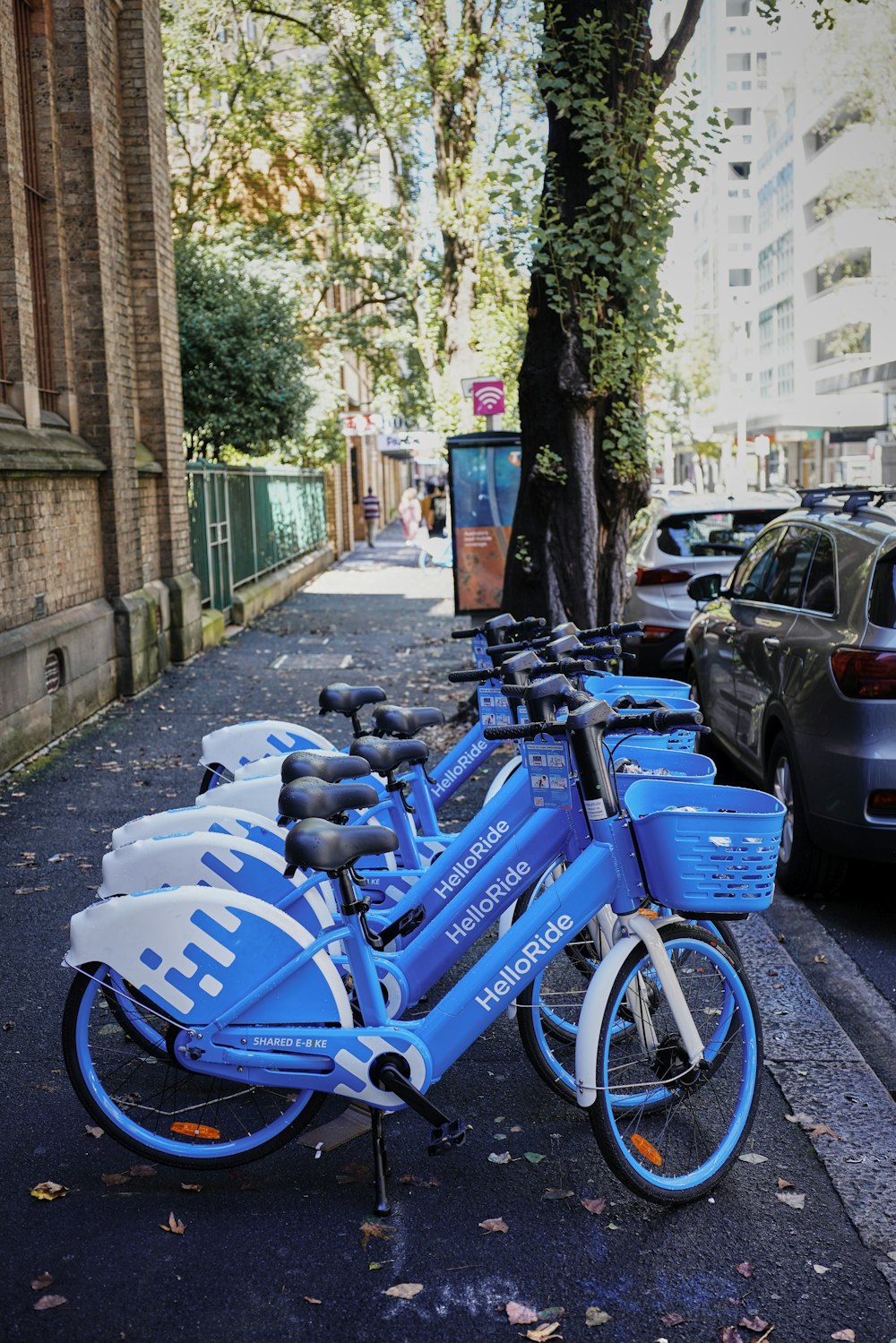 a row of blue bicycles parked on the side of a street