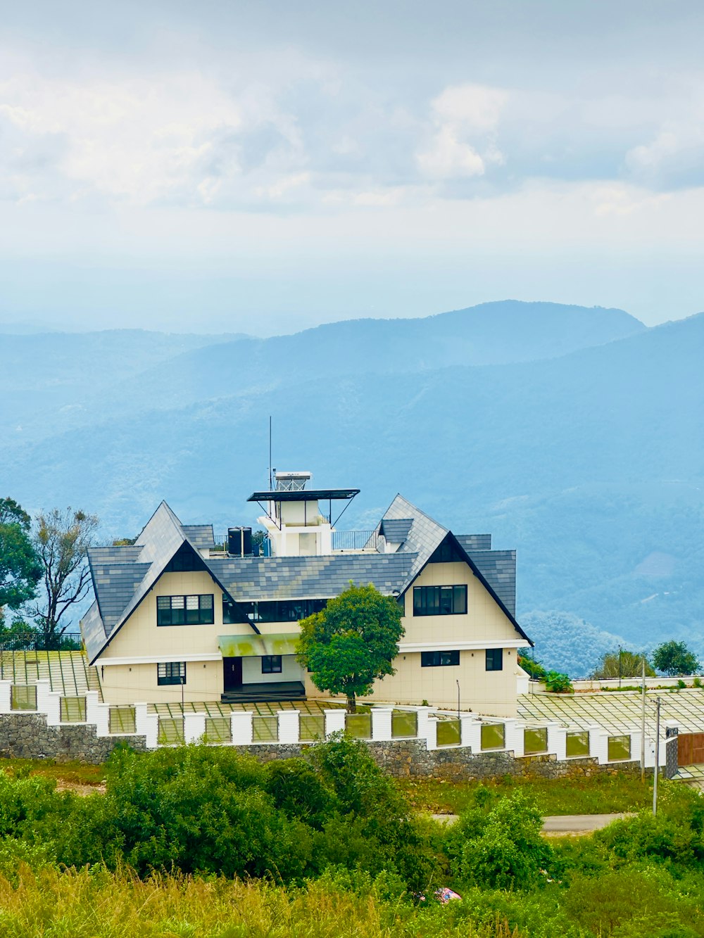 a large white house sitting on top of a lush green hillside