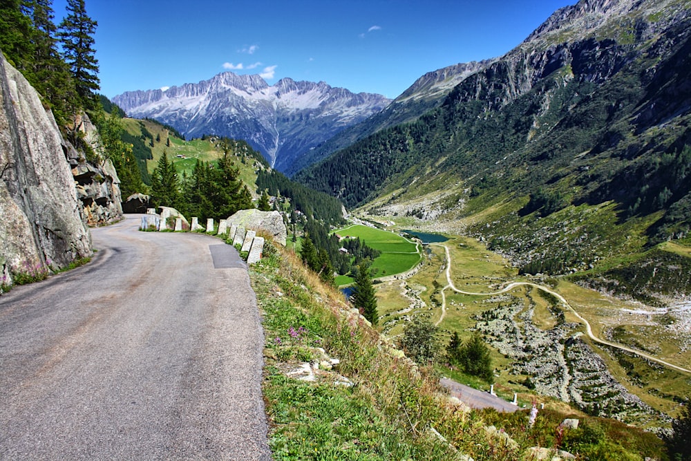 a road winding through a valley with mountains in the background