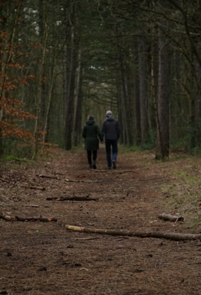 two people walking down a path in the woods