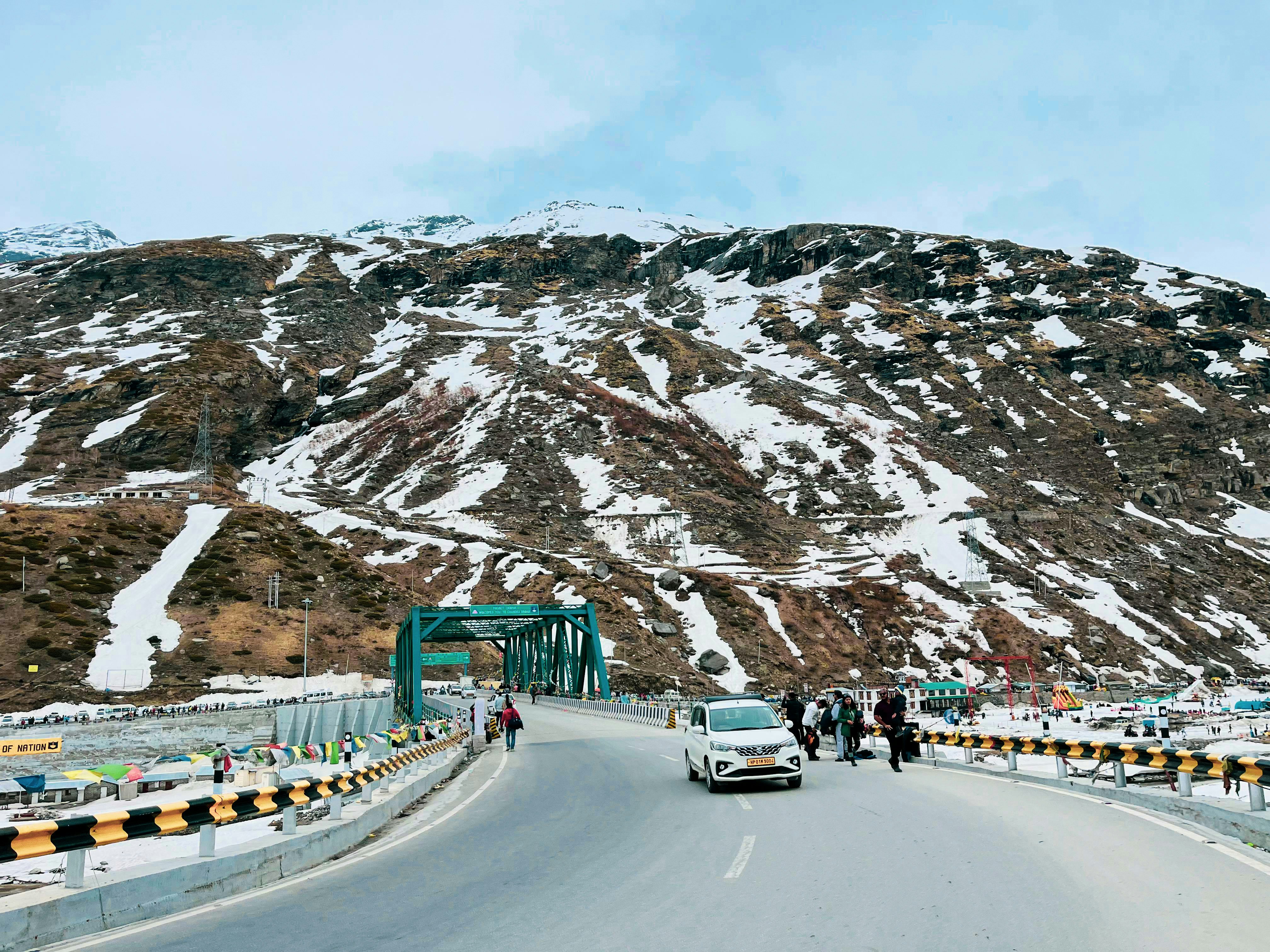 a car driving down a road next to a mountain