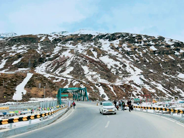 a car driving down a road next to a mountain
