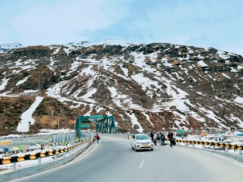 a car driving down a road next to a mountain