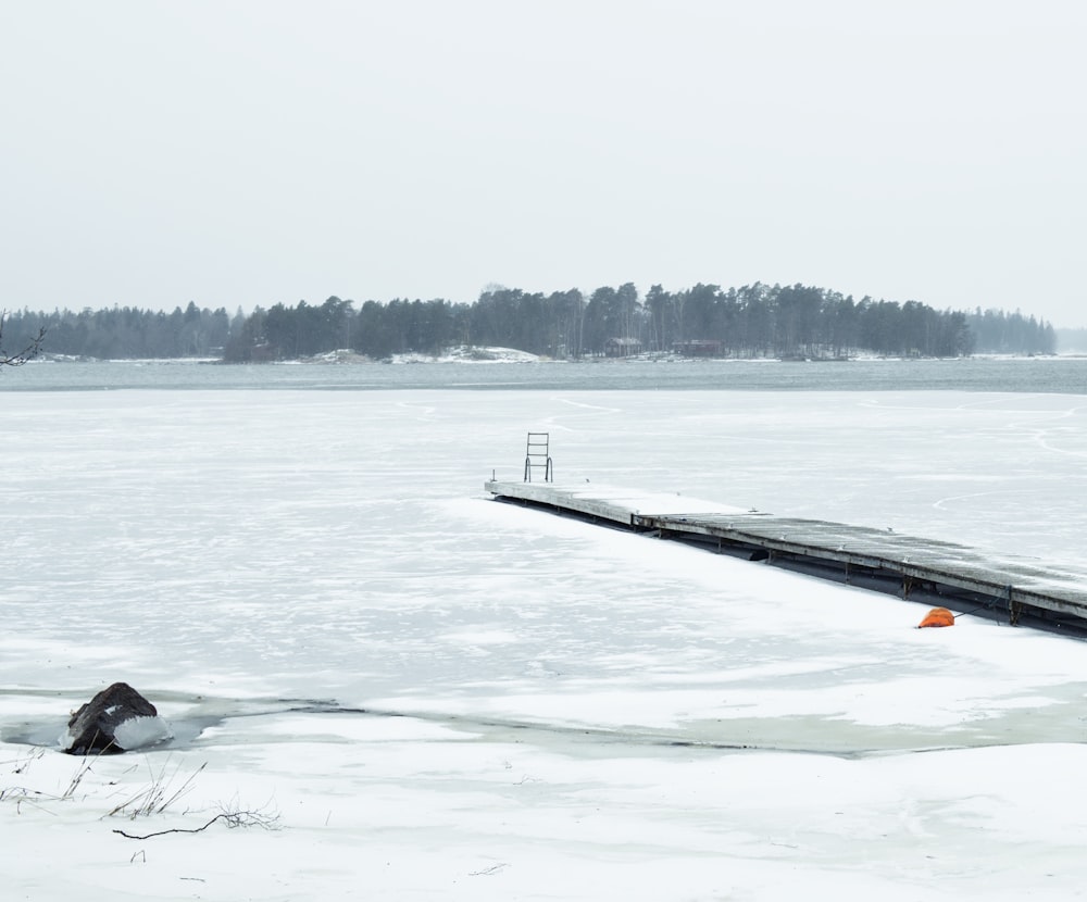 a long wooden dock sitting on top of a frozen lake