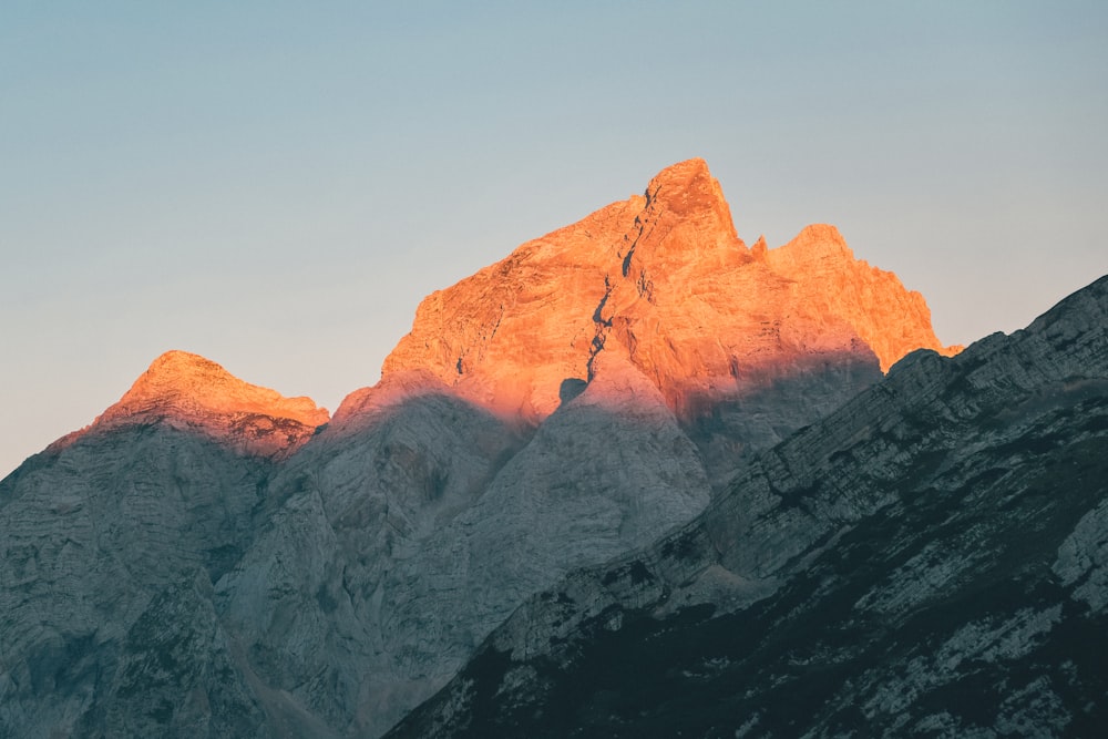 the sun is setting on a mountain peak