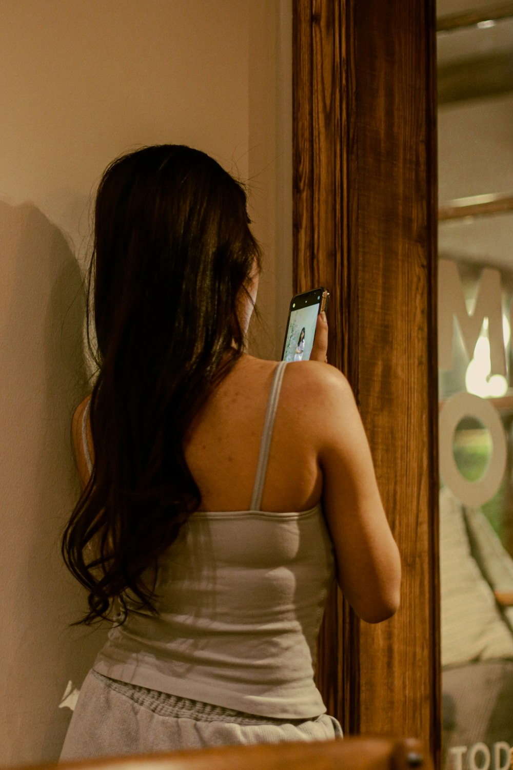 a woman looking at her cell phone in a mirror