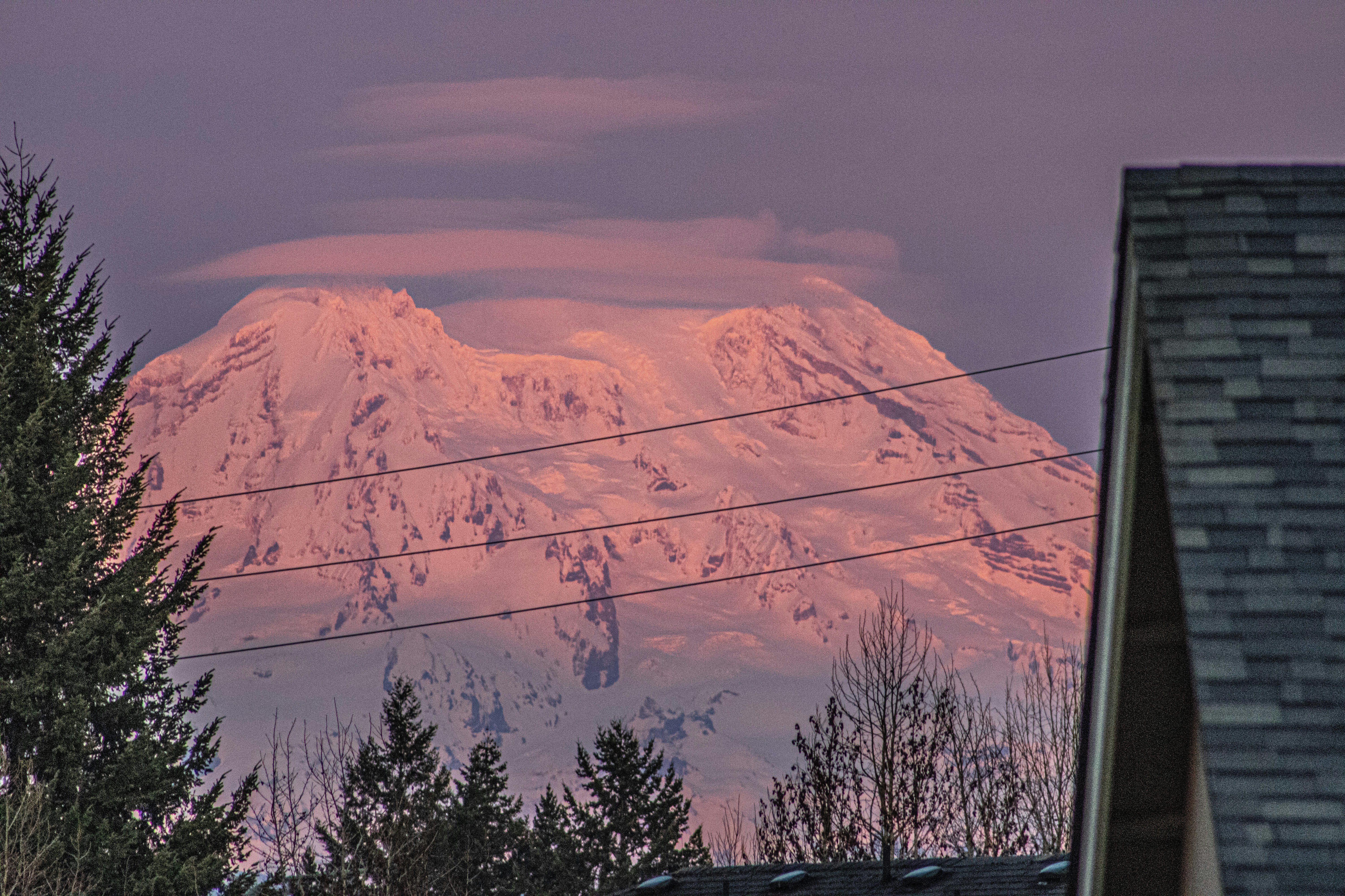 a snow covered mountain in the distance with power lines in the foreground