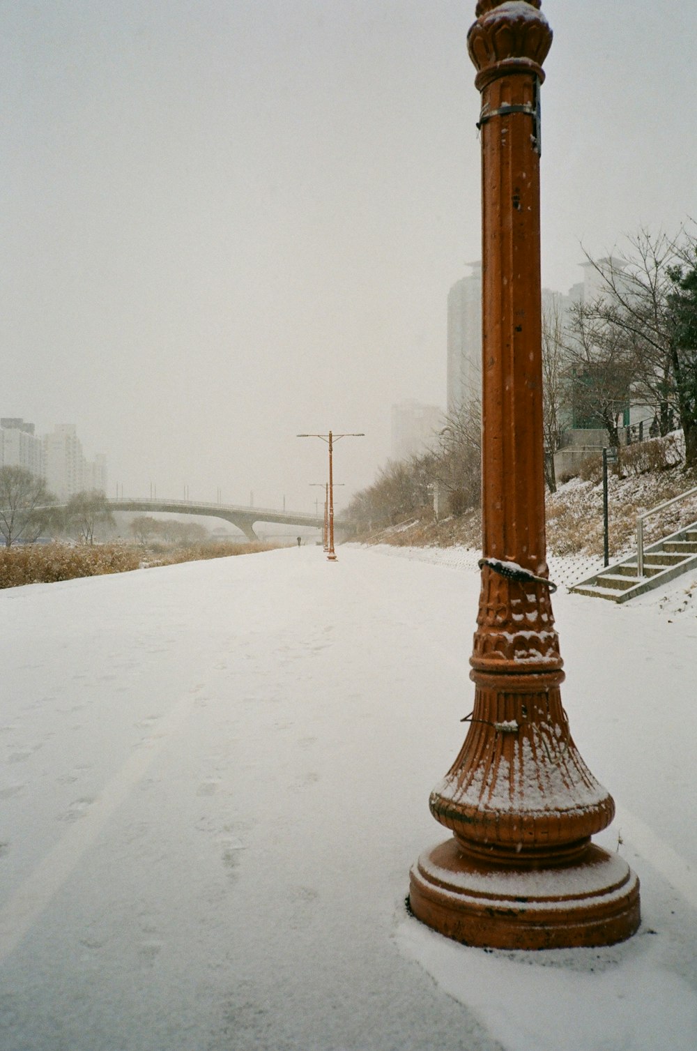 a street light covered in snow next to a bridge