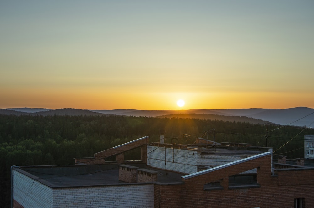 the sun is setting over a building in the mountains