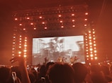 a crowd of people watching a concert on a large screen