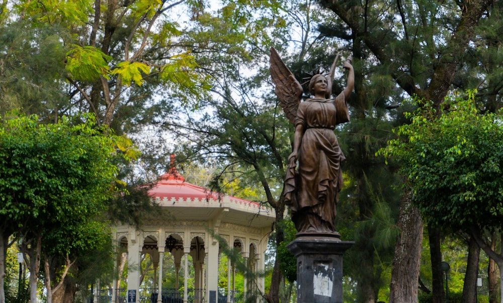 a statue of a woman holding a bird in a park