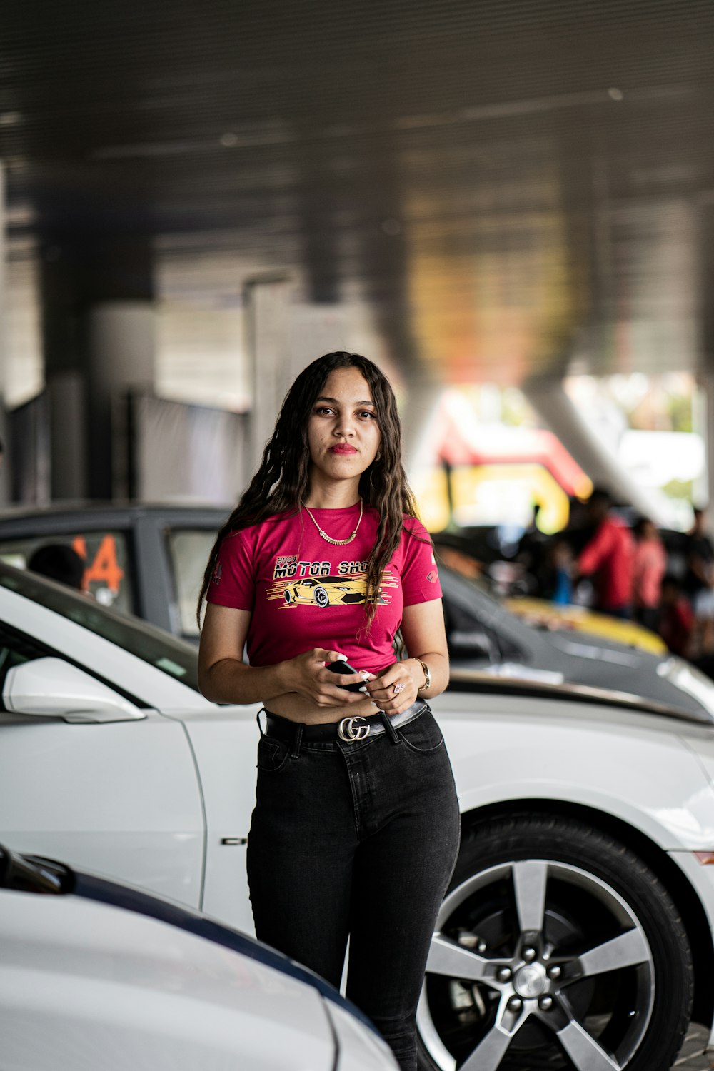 a woman in a pink shirt standing next to a white car