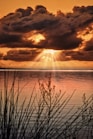 the sun is shining through the clouds over the water