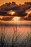 the sun is shining through the clouds over the water