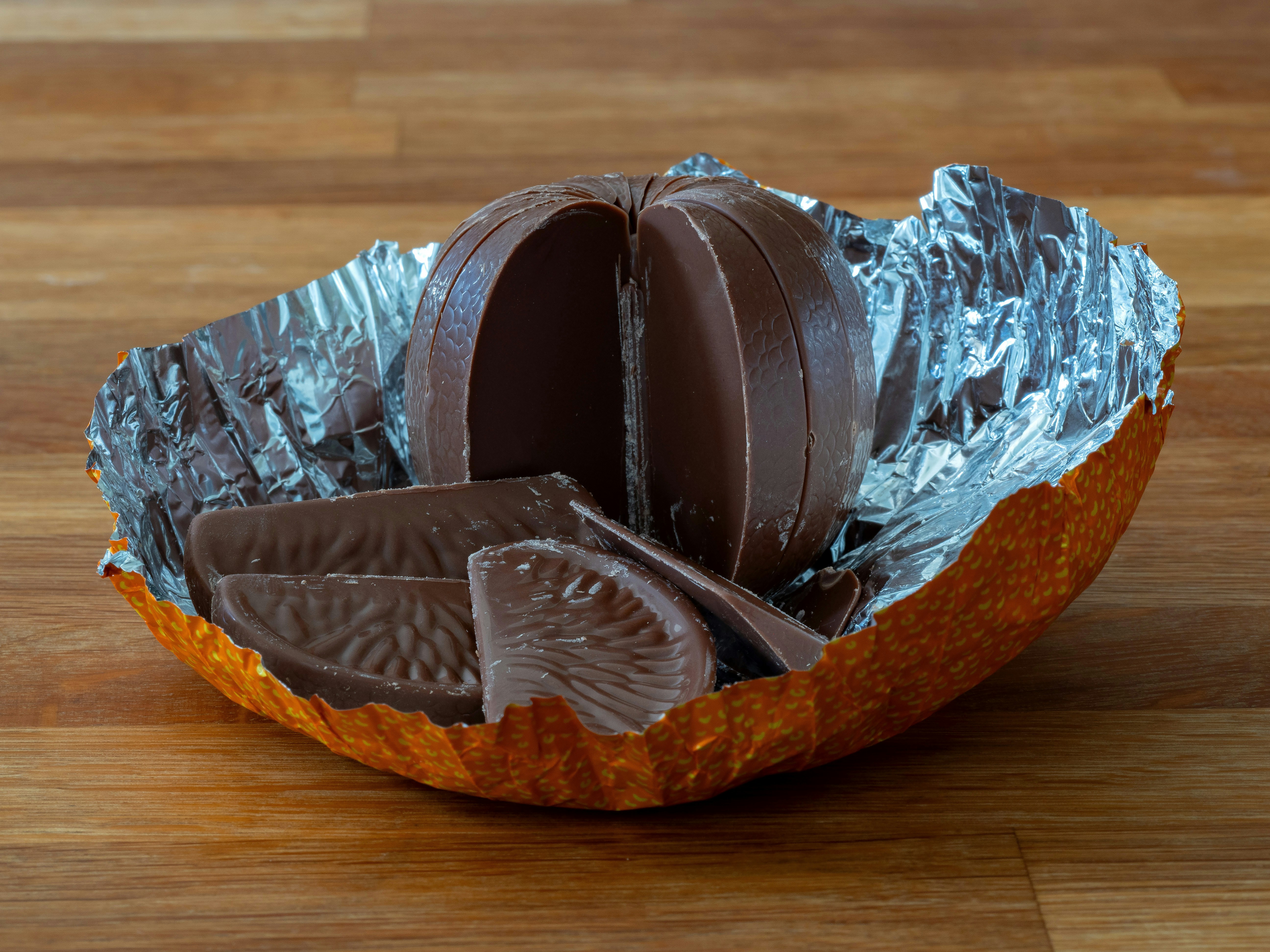 a piece of chocolate in a foil wrapper on a wooden table