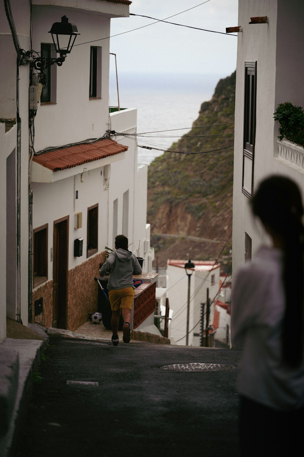 a woman walking down a street next to a tall white building