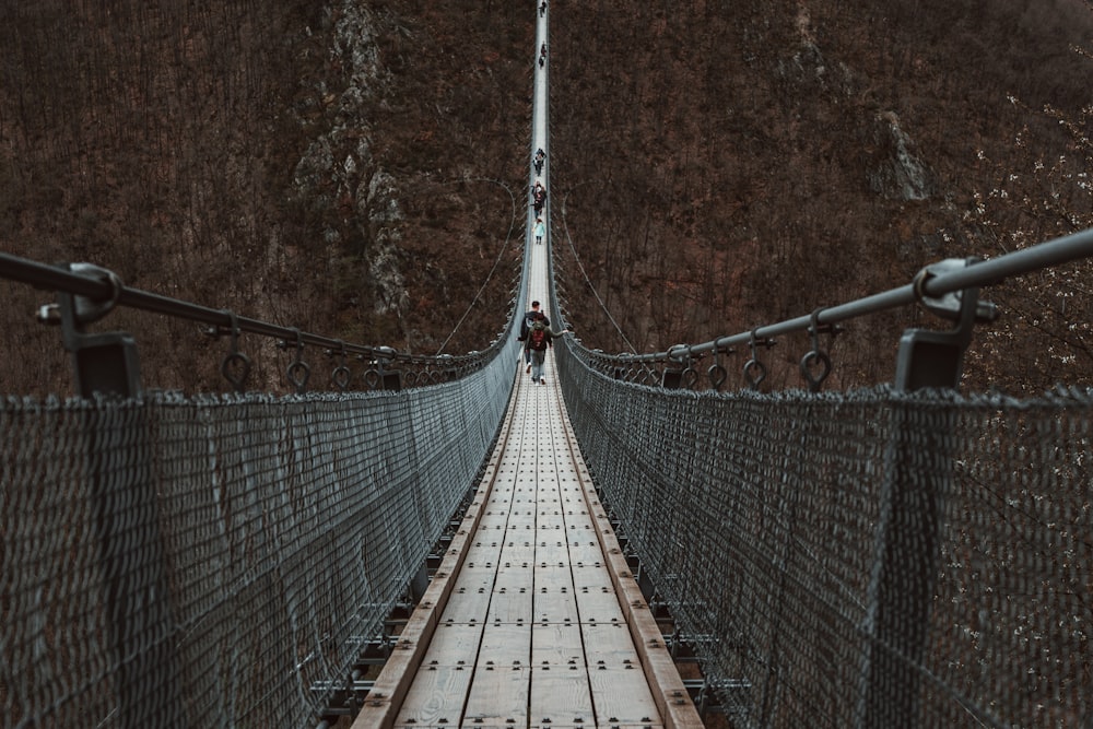 a man walking across a suspension bridge over a river