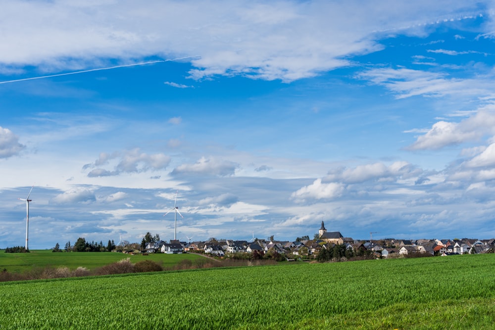 a green field with houses in the distance