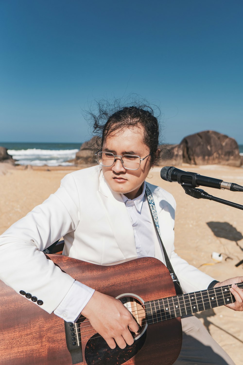 a woman playing a guitar on the beach