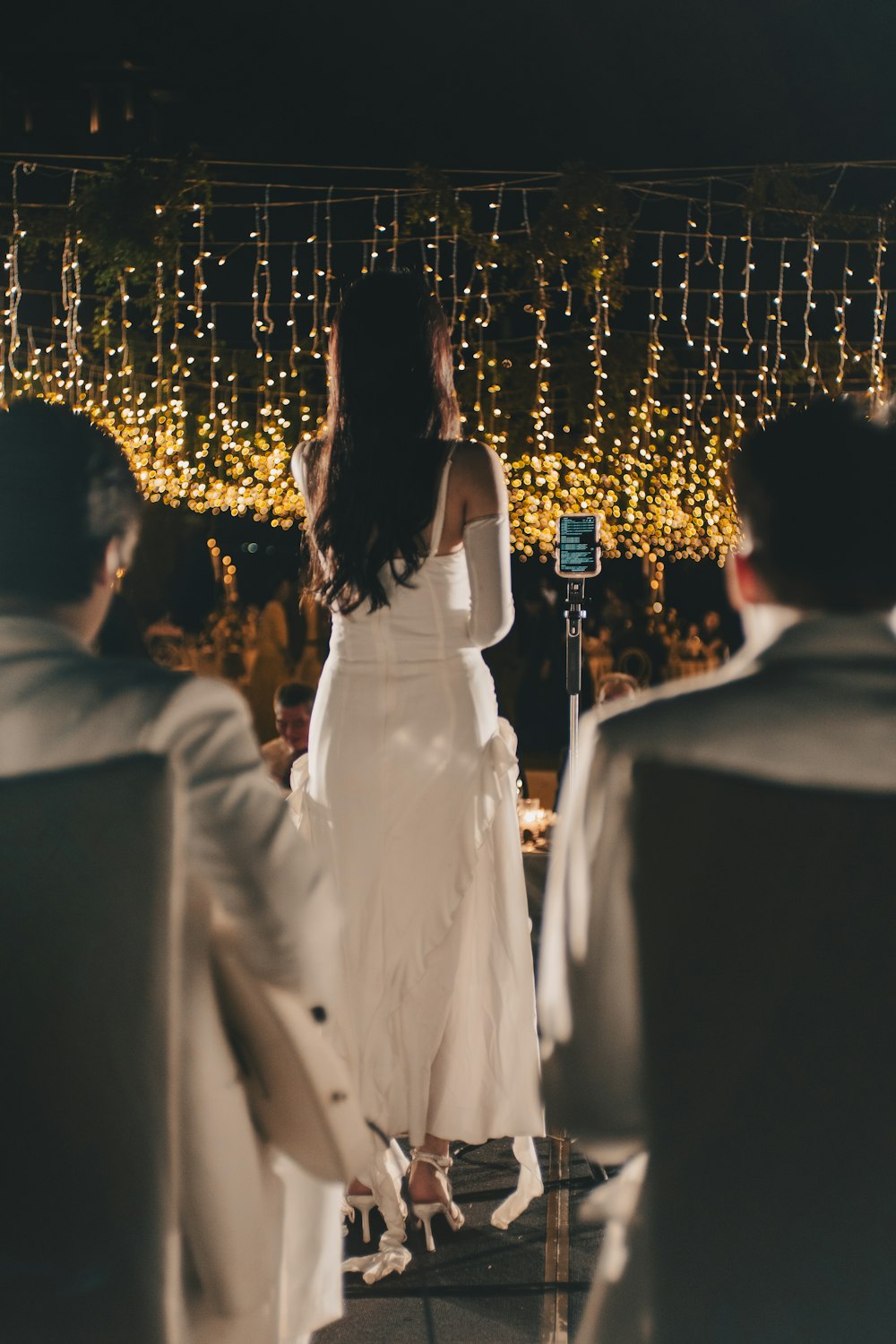 a woman in a white dress standing in front of a group of people